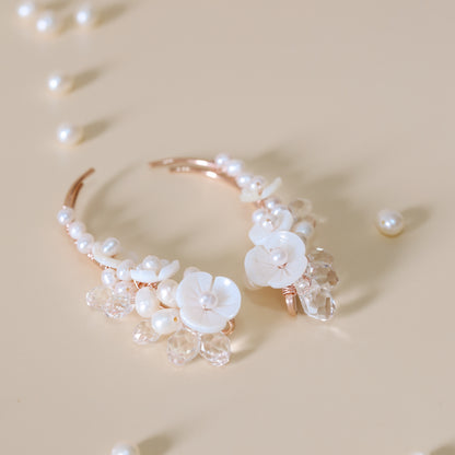 Close-up of matching bridal ear climbers decorated with AA+ freshwater pearls, carved mother-of-pearl flowers and transparent faceted crystal drops, showing the coordinated left and right design.