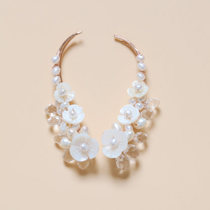 Close-up of matching bridal ear climbers decorated with AA+ freshwater pearls, carved mother-of-pearl flowers and transparent faceted crystal drops, showing the coordinated left and right design.