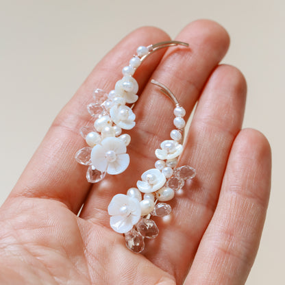 Statement floral bridal ear climber worn from the lobe upward, featuring natural pearl accents, shell flowers and transparent faceted crystals designed to catch the light.