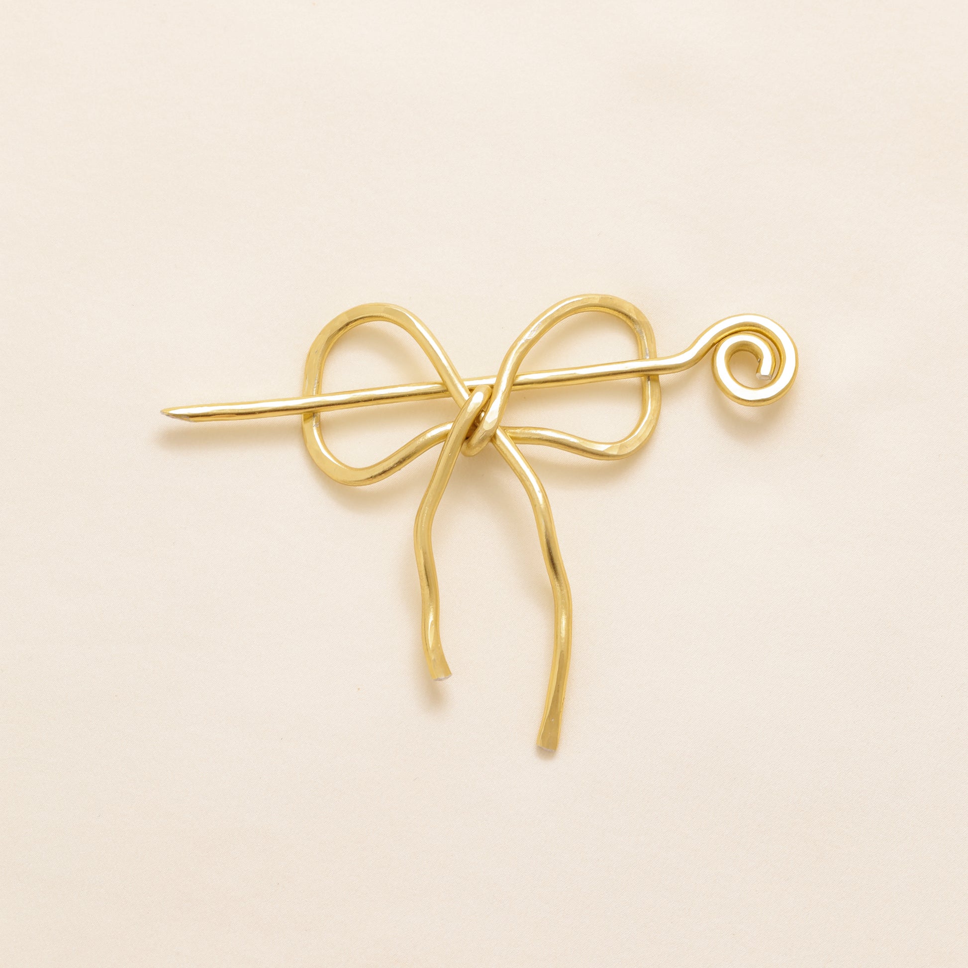 Handmade aluminum bow shawl pin brooch with matching removable stick pin, shown in gold and available in silver or gold finish, designed as a decorative and functional scarf fastener for shawls, sweaters, cardigans, knit wraps and crochet pieces, with a romantic bow shape and minimalist metal design.