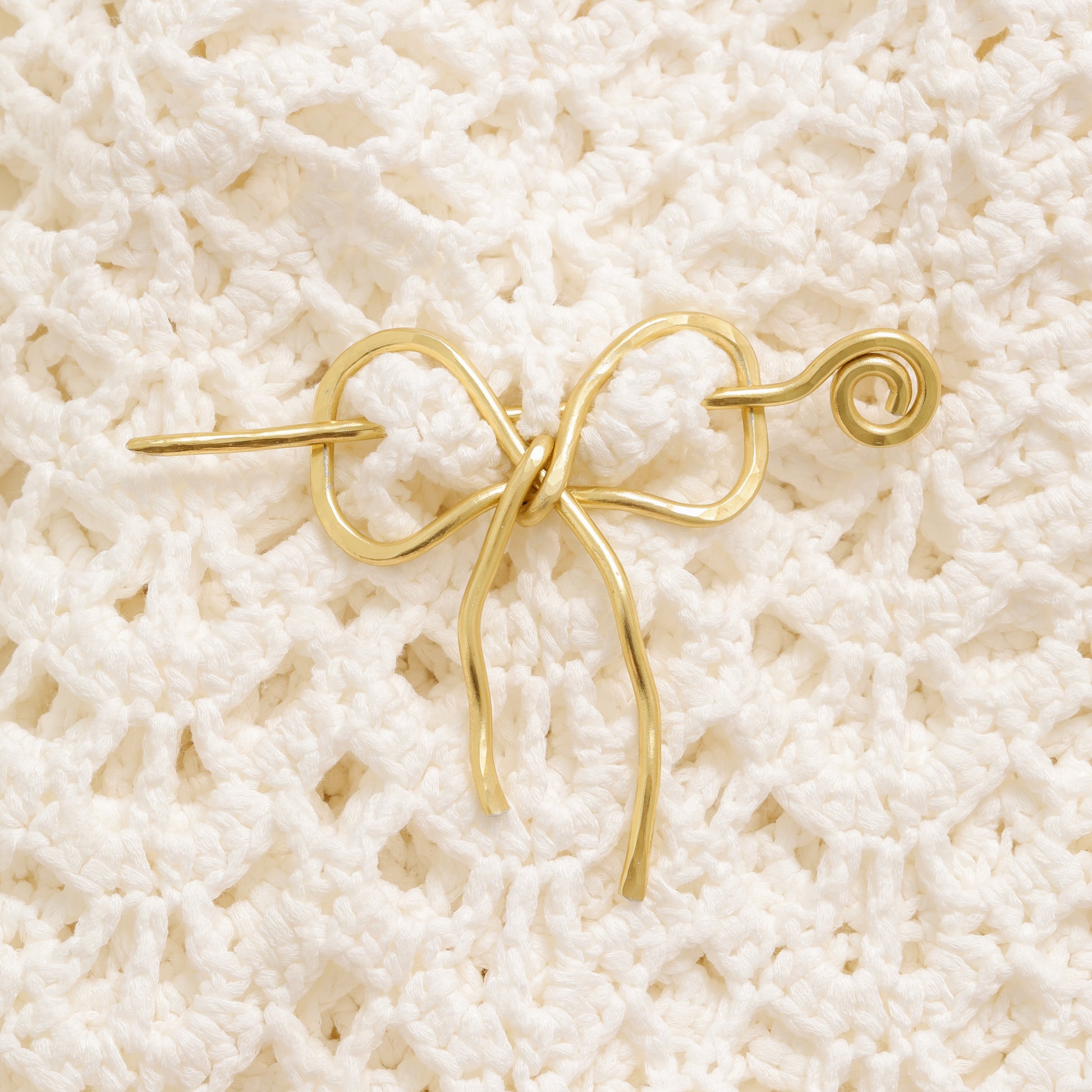 Handmade aluminum bow shawl pin brooch with matching removable stick pin, shown in gold and available in silver or gold finish, designed as a decorative and functional scarf fastener for shawls, sweaters, cardigans, knit wraps and crochet pieces, with a romantic bow shape and minimalist metal design.