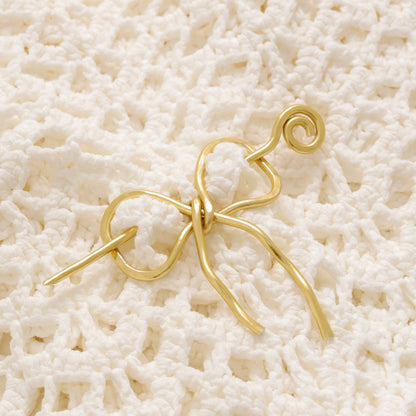 Handmade aluminum bow shawl pin brooch with matching removable stick pin, shown in gold and available in silver or gold finish, designed as a decorative and functional scarf fastener for shawls, sweaters, cardigans, knit wraps and crochet pieces, with a romantic bow shape and minimalist metal design.