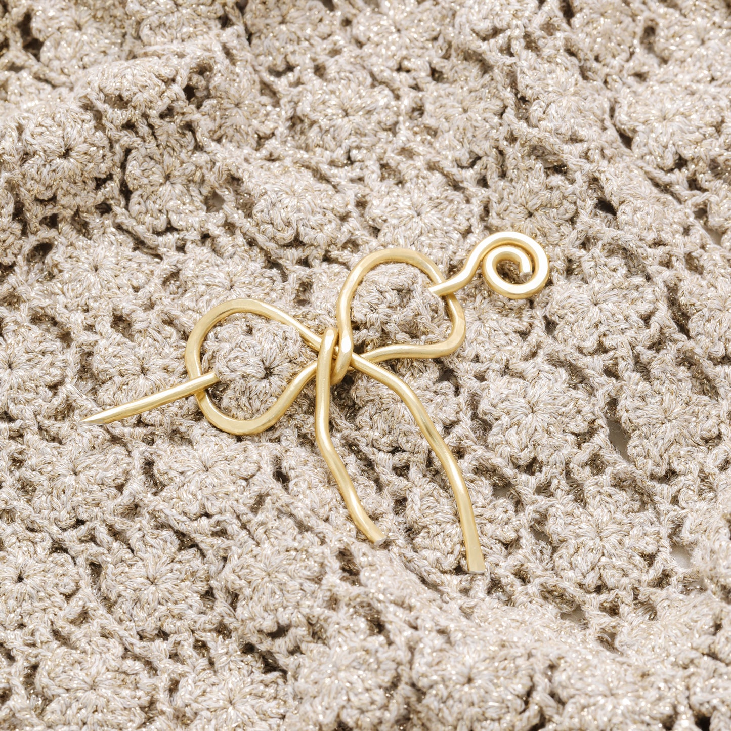 Handmade aluminum bow shawl pin brooch with matching removable stick pin, shown in gold and available in silver or gold finish, designed as a decorative and functional scarf fastener for shawls, sweaters, cardigans, knit wraps and crochet pieces, with a romantic bow shape and minimalist metal design.