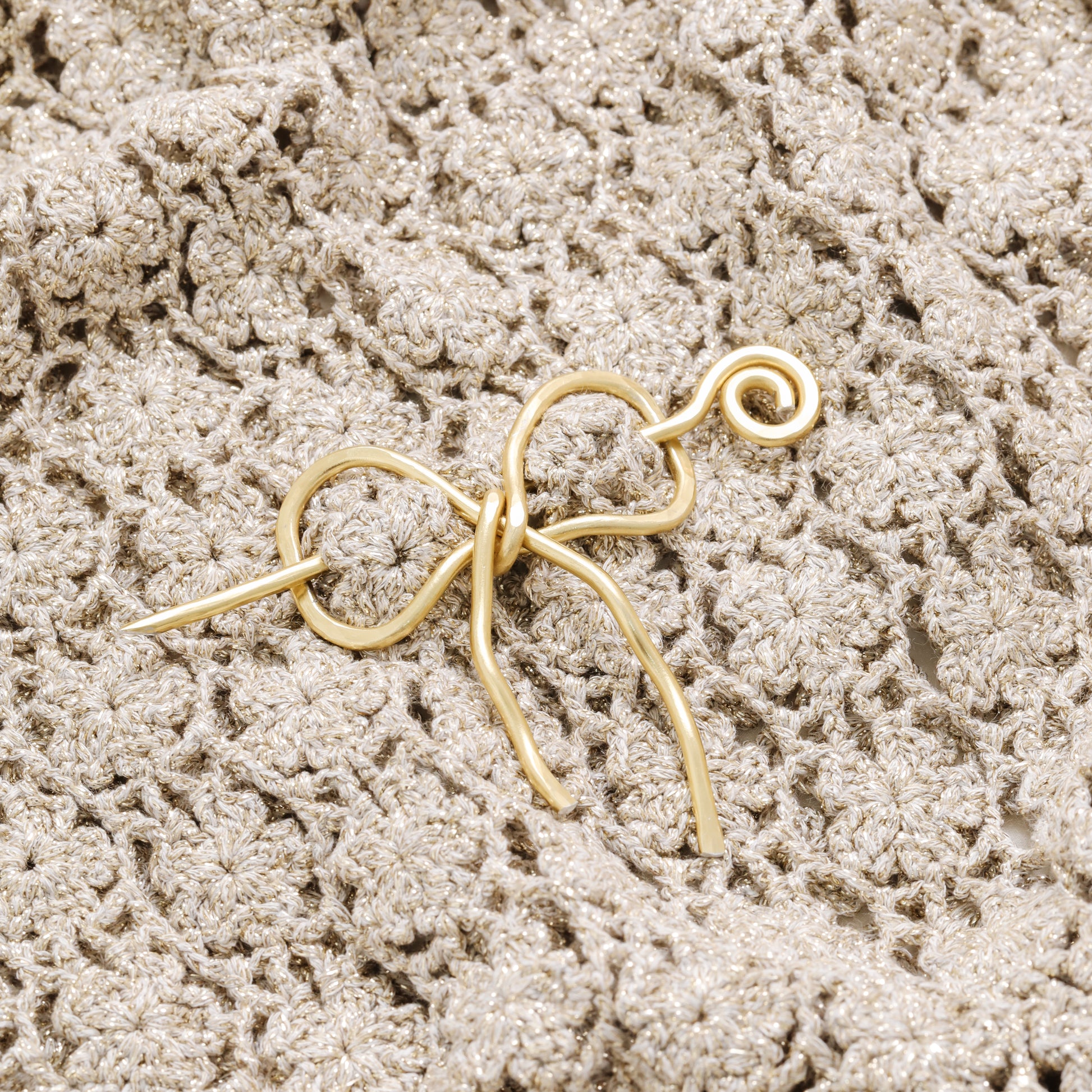 Handmade aluminum bow shawl pin brooch with matching removable stick pin, shown in gold and available in silver or gold finish, designed as a decorative and functional scarf fastener for shawls, sweaters, cardigans, knit wraps and crochet pieces, with a romantic bow shape and minimalist metal design.