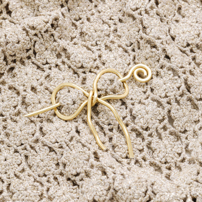 Handmade aluminum bow shawl pin brooch with matching removable stick pin, shown in gold and available in silver or gold finish, designed as a decorative and functional scarf fastener for shawls, sweaters, cardigans, knit wraps and crochet pieces, with a romantic bow shape and minimalist metal design.
