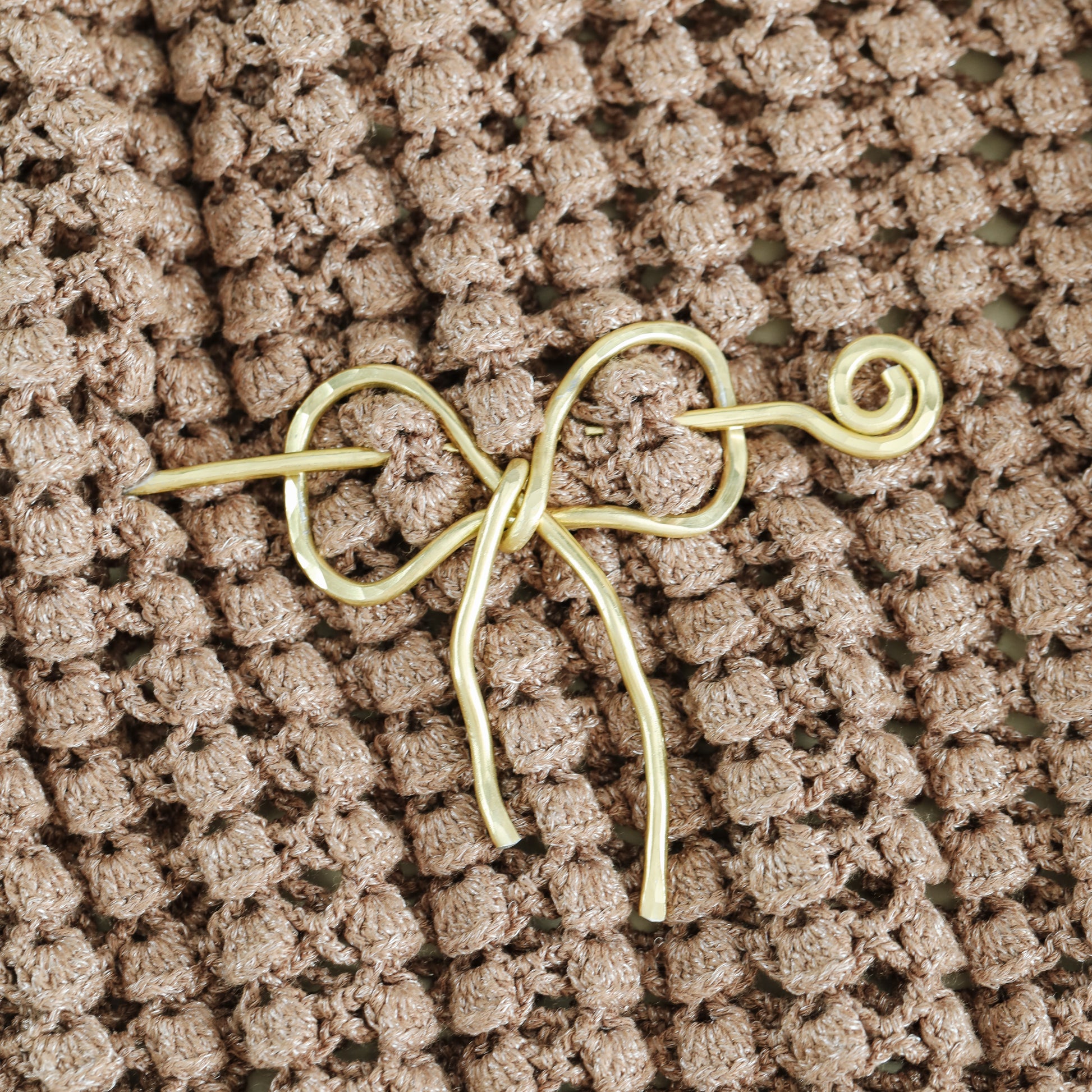 Handmade aluminum bow shawl pin brooch with matching removable stick pin, shown in gold and available in silver or gold finish, designed as a decorative and functional scarf fastener for shawls, sweaters, cardigans, knit wraps and crochet pieces, with a romantic bow shape and minimalist metal design.