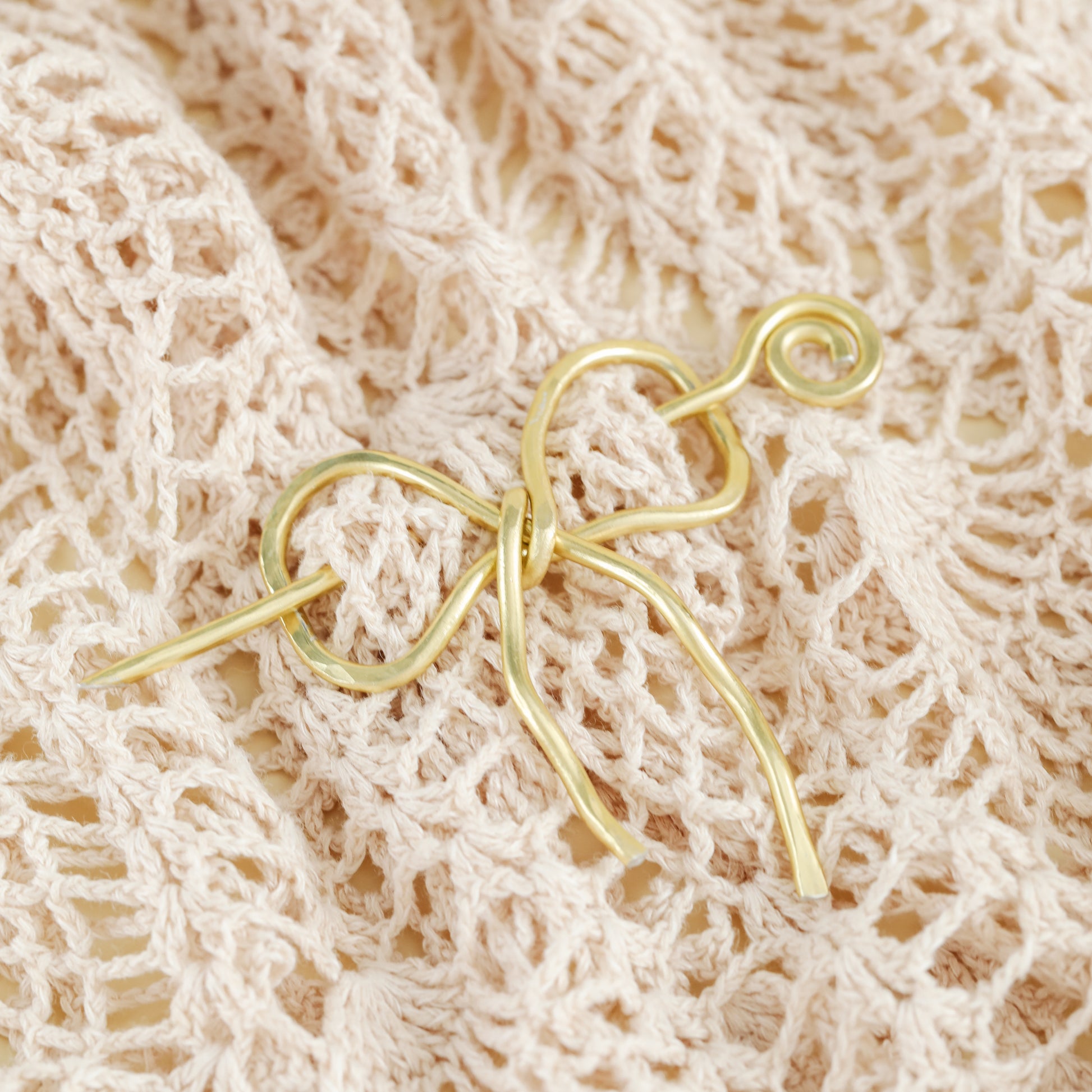 Handmade aluminum bow shawl pin brooch with matching removable stick pin, shown in gold and available in silver or gold finish, designed as a decorative and functional scarf fastener for shawls, sweaters, cardigans, knit wraps and crochet pieces, with a romantic bow shape and minimalist metal design.