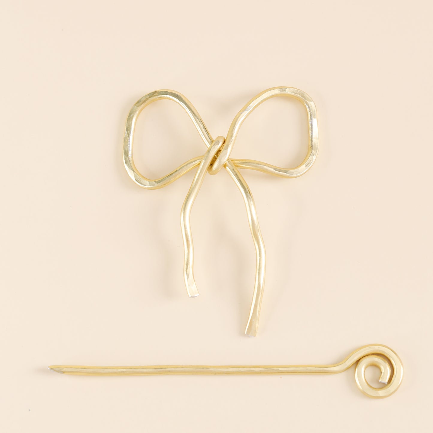 Handmade aluminum bow shawl pin brooch with matching removable stick pin, shown in gold and available in silver or gold finish, designed as a decorative and functional scarf fastener for shawls, sweaters, cardigans, knit wraps and crochet pieces, with a romantic bow shape and minimalist metal design.