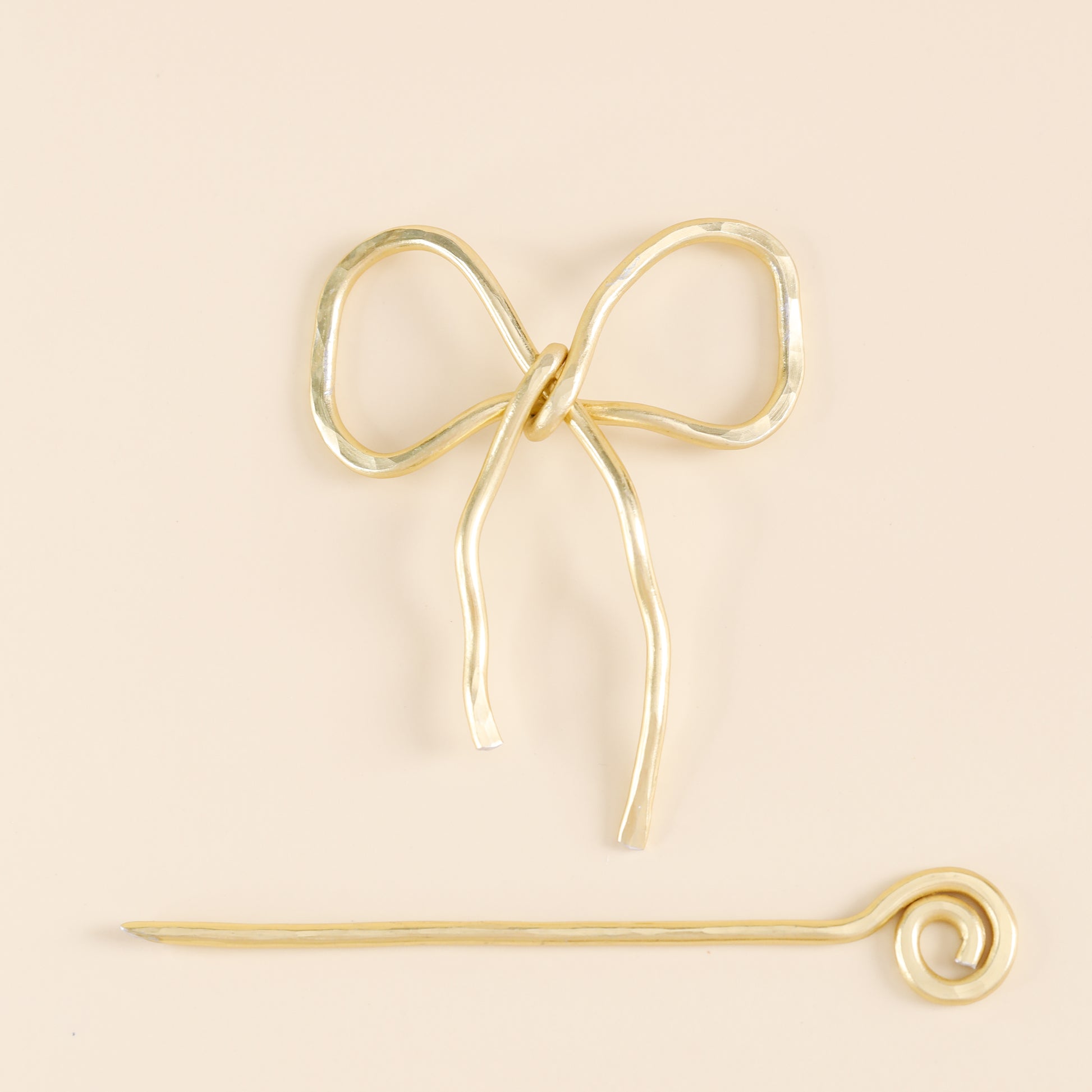 Handmade aluminum bow shawl pin brooch with matching removable stick pin, shown in gold and available in silver or gold finish, designed as a decorative and functional scarf fastener for shawls, sweaters, cardigans, knit wraps and crochet pieces, with a romantic bow shape and minimalist metal design.