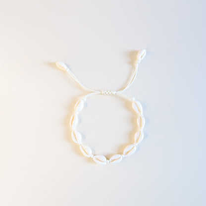 Close up of cream cotton cord anklet with natural cowrie shells and sliding knot closure