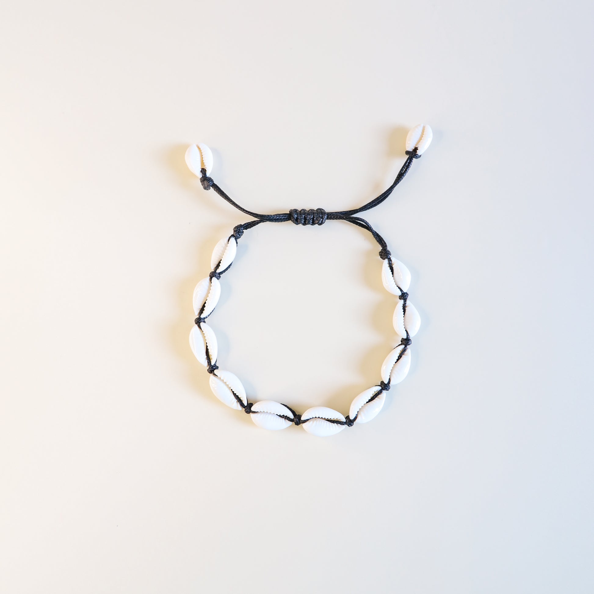 Adjustable cowrie shell anklet with black cotton cord and natural white shells