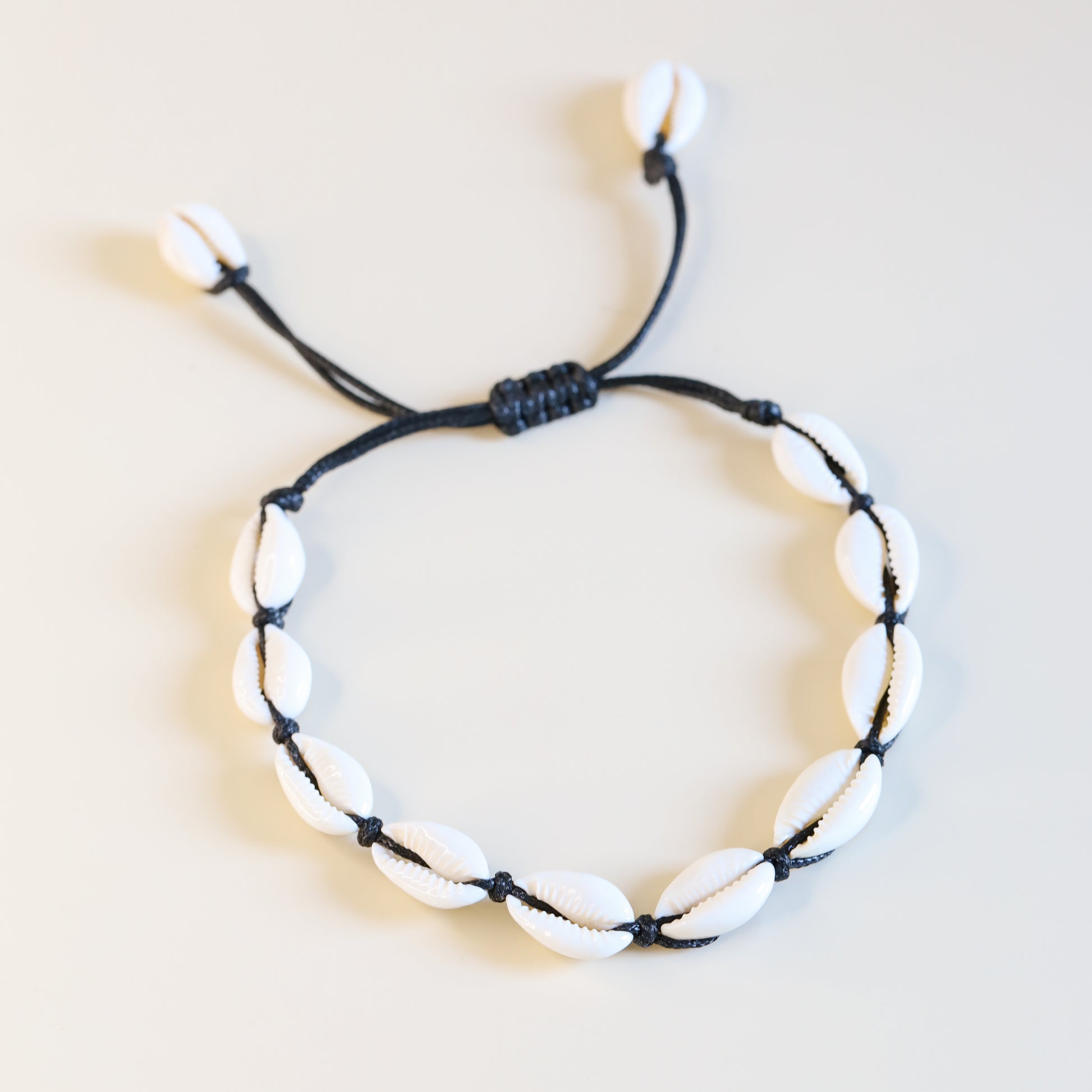 Adjustable cowrie shell anklet with black cotton cord and natural white shells