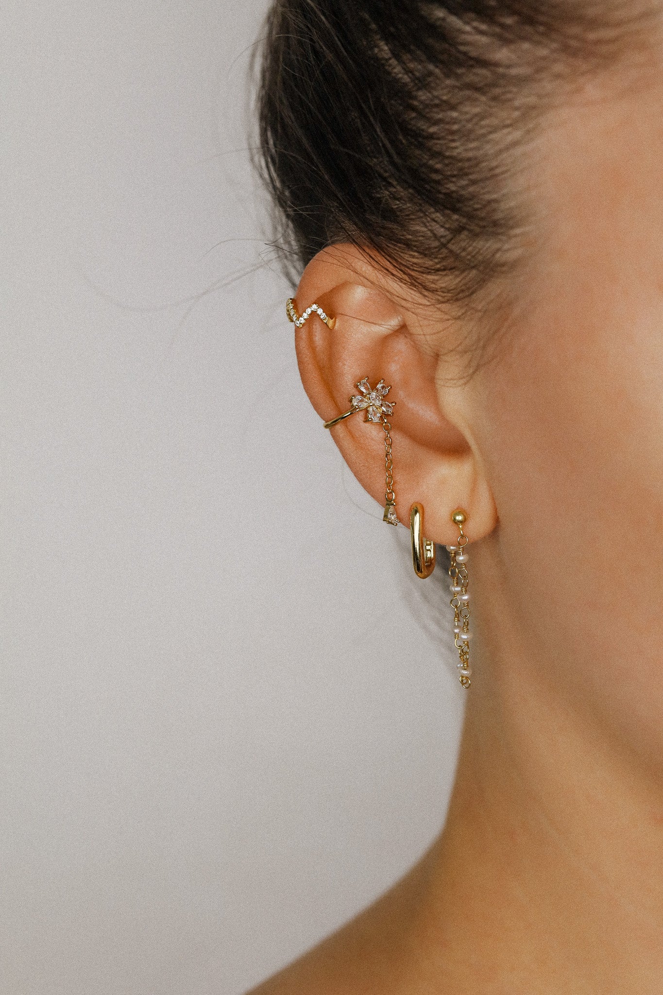 Sparkling flower ear cuff with dainty drop chain in 18k gold plated sterling silver and 925 silver, worn on cartilage without piercing.