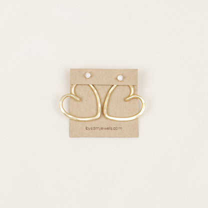 Handmade open heart Ear Jacket earrings designed to sit behind the pierced earlobe beneath an interchangeable stud, available as One Ear Jacket or a matching Pair of Ear Jackets in gold or silver hammered aluminum, approximately 25 mm in diameter, with stainless steel post studs; one surprise pair of stud earrings is included with each order and selected from currently available styles, so the studs shown in the photos are examples and specific designs cannot be guaranteed.