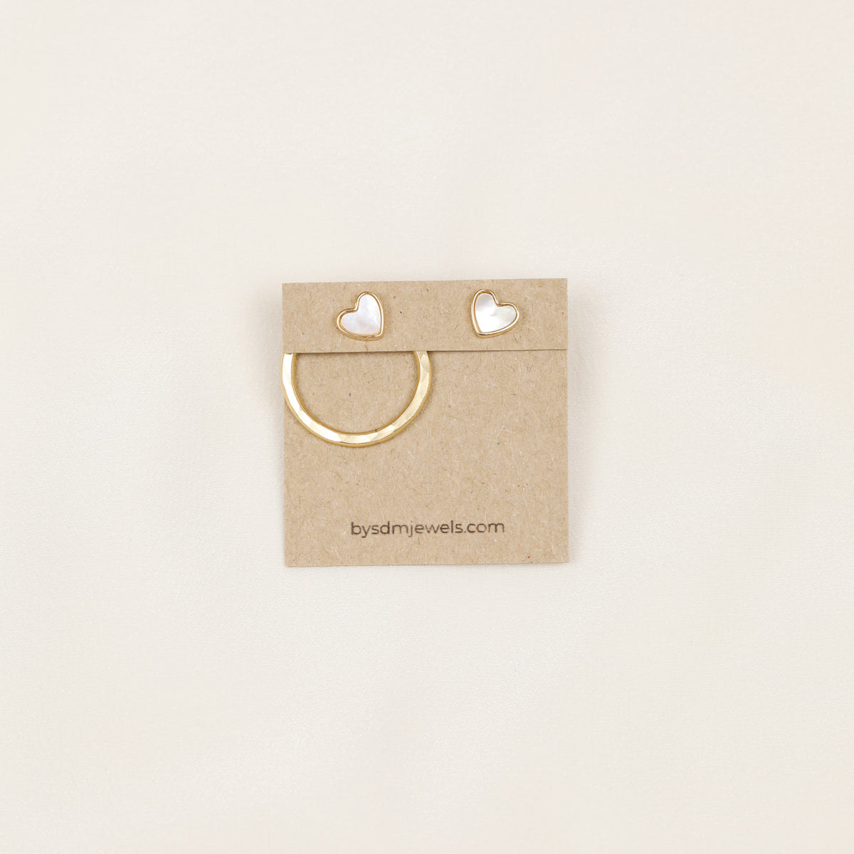 Gold round ear jacket displayed with a white heart stud, showing how the removable circular jacket can be combined with different stud earrings.