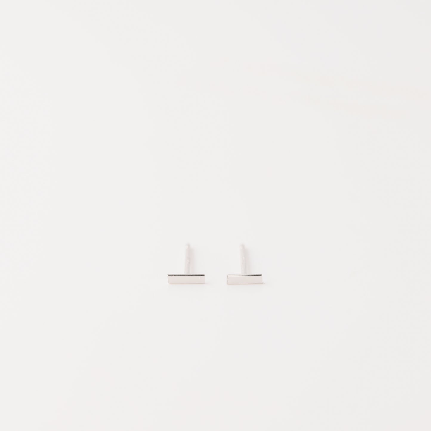 Tiny rectangle bar stud earrings in solid 925 sterling silver on white background