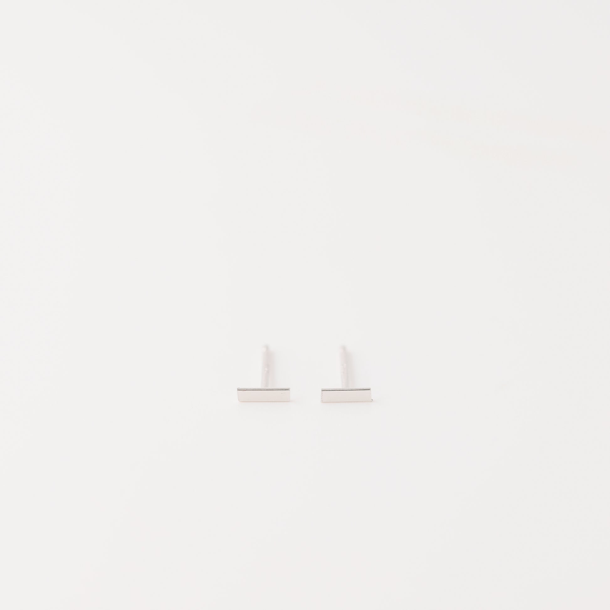 Tiny rectangle bar stud earrings in solid 925 sterling silver on white background