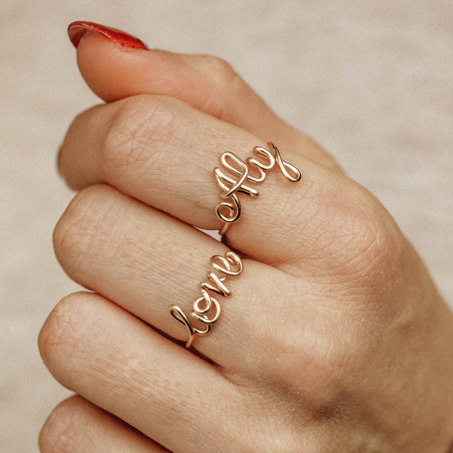 Two custom gold wire name rings featuring "Aly" and "Love" worn together for a stacking effect.