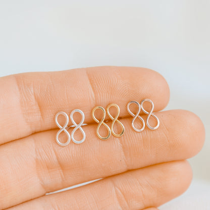 Small infinity symbol earrings shown on fingers for size reference