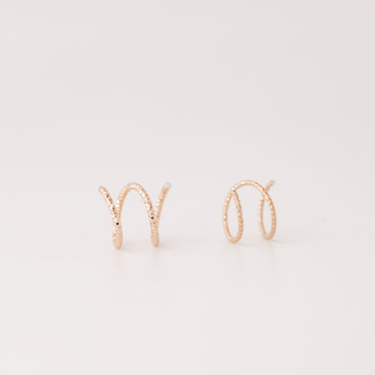 Close-up of a woman's ear wearing tiny rose gold double hoop illusion earrings with a diamond-cut texture, designed to create the appearance of two piercings with a single hole.