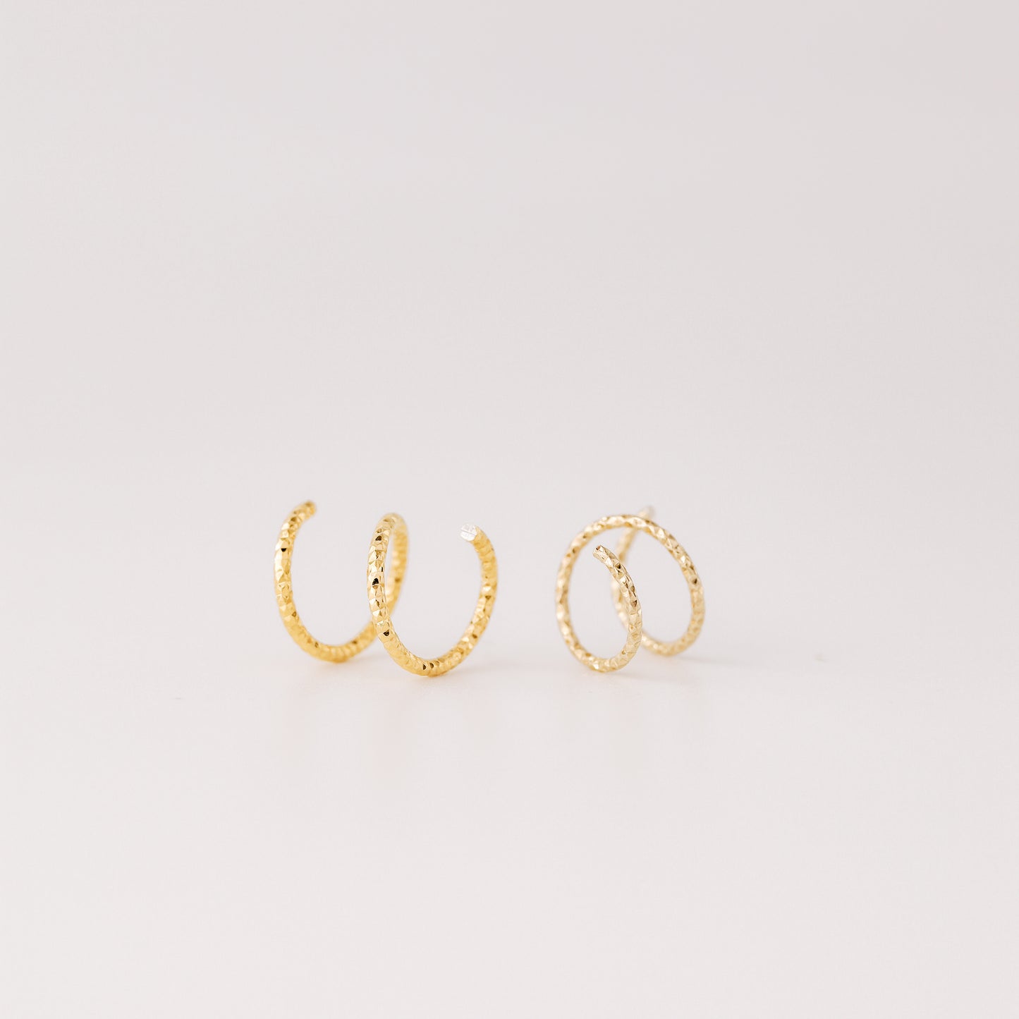 Minimal gold double hoop earrings with spiral twist design worn on ear, illusion of double piercing, diamond cut sterling silver jewelry