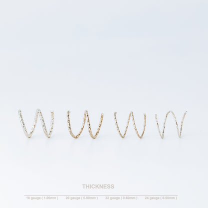 Minimal black double hoop spiral earrings worn on ear, tiny ruthenium sterling silver illusion hoops creating double piercing look, diamond cut texture close-up