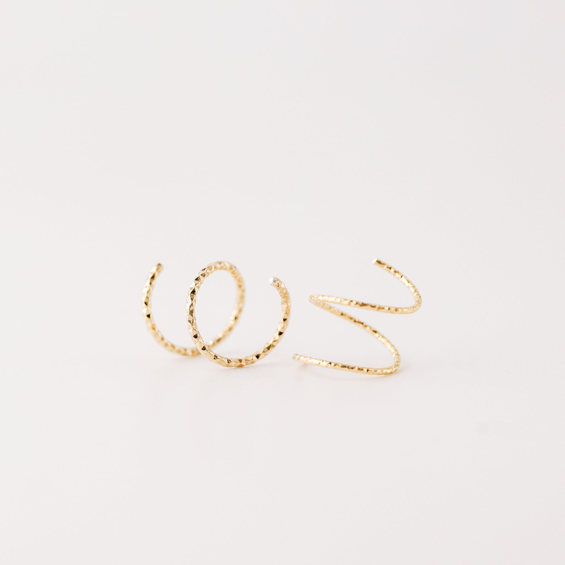 Minimal gold double hoop earrings with spiral twist design worn on ear, illusion of double piercing, diamond cut sterling silver jewelry