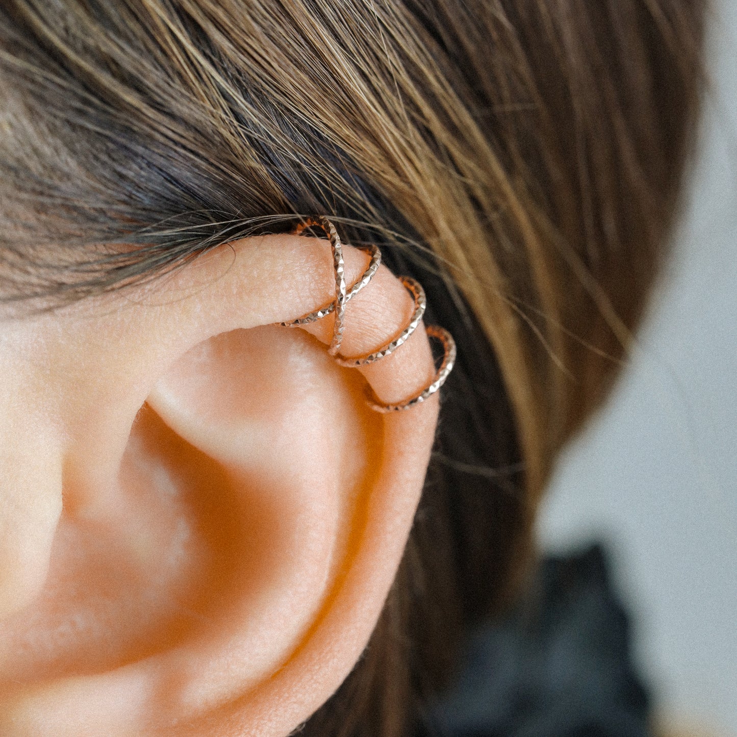 No-piercing double line and criss cross helix ear cuff worn on the upper ear, available in smooth and diamond cut finish options for cartilage styling.