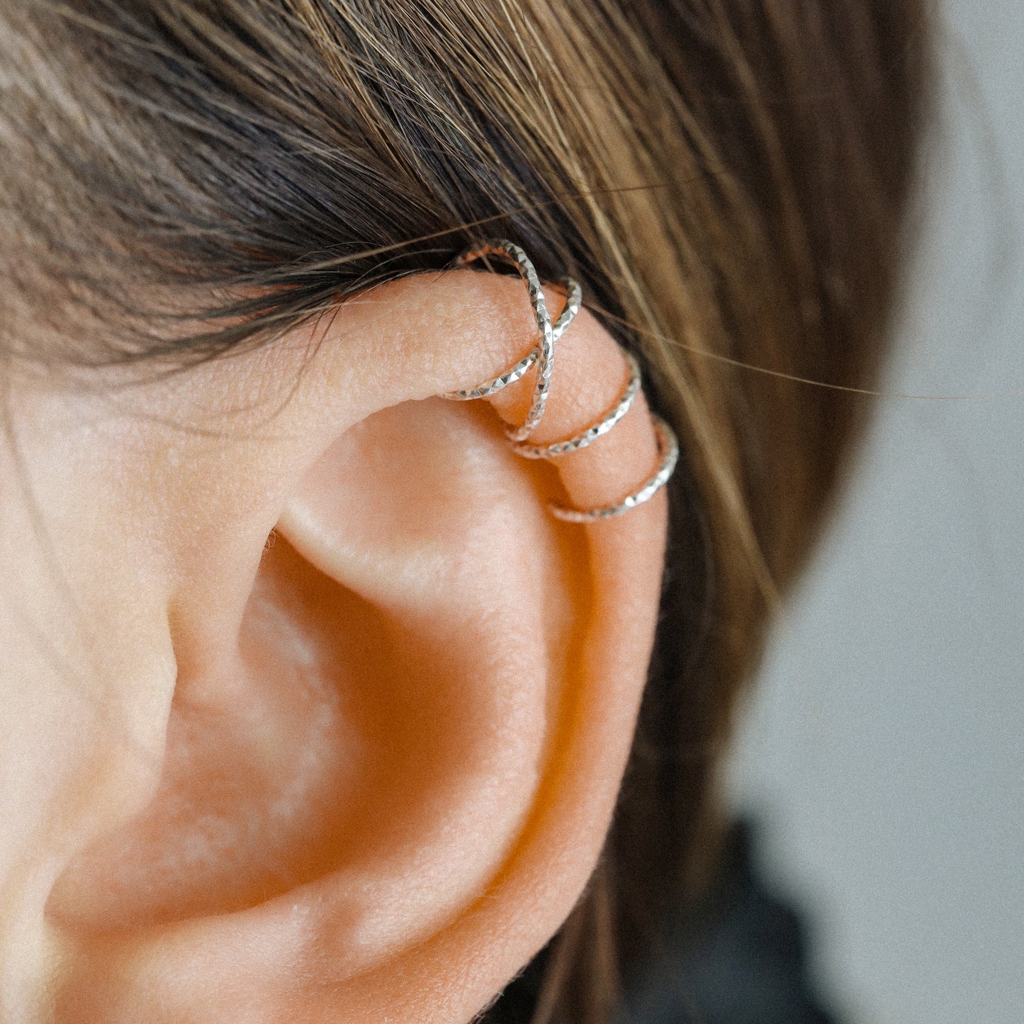 No-piercing double line and criss cross helix ear cuff shown on the upper ear, with smooth and diamond cut finish options for cartilage styling.