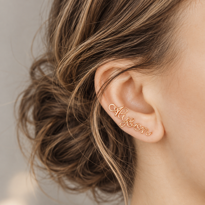 Handmade personalized name ear climber worn across the lobe through one standard piercing, featuring a custom flowing wire script design made with the chosen name or word up to 10 characters, available as a single left ear climber, single right ear climber or pair in solid 925 sterling silver, 14k gold filled and 14k rose gold filled.