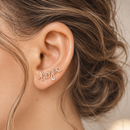Handmade personalized name ear climber worn across the lobe through one standard piercing, featuring a custom flowing wire script design made with the chosen name or word up to 10 characters, available as a single left ear climber, single right ear climber or pair in solid 925 sterling silver, 14k gold filled and 14k rose gold filled.