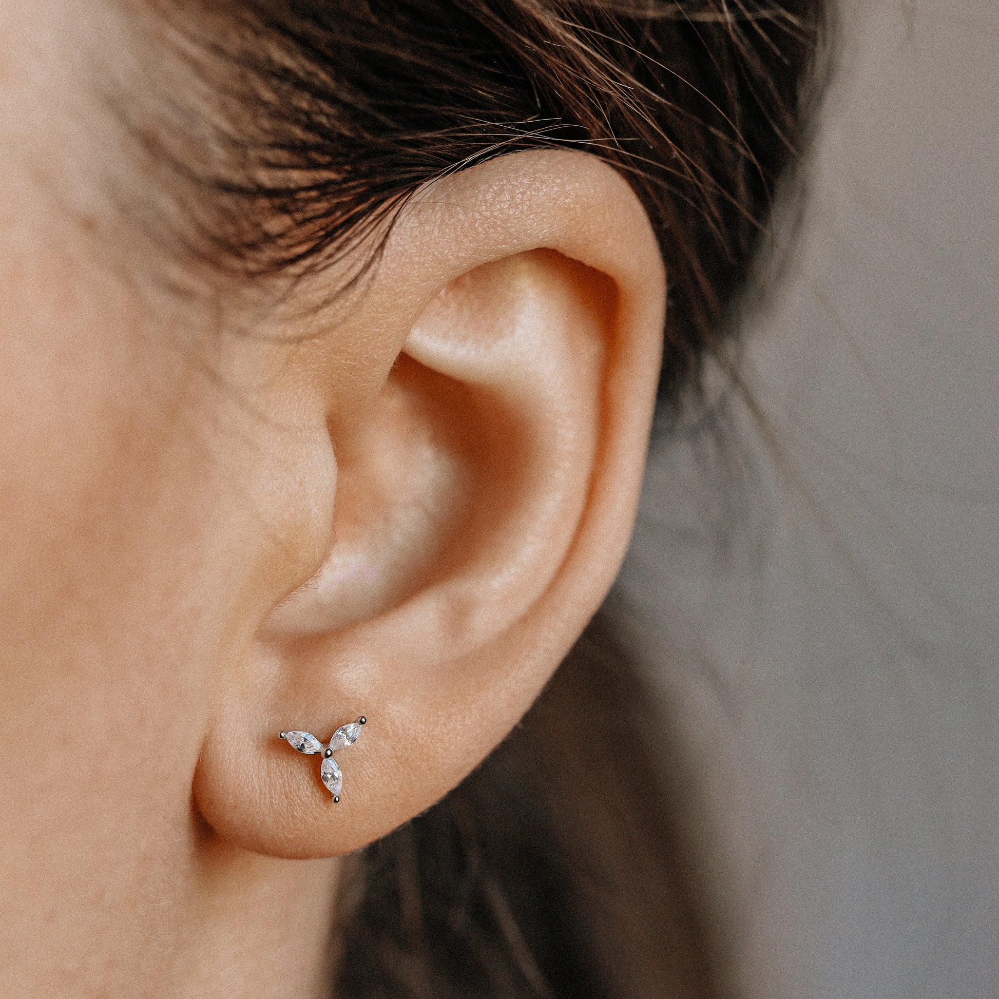 Tiny marquise stud earring worn on lobe piercing close-up