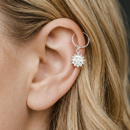 Close-up of the diamond-cut texture on a silver celestial sun hoop earring.