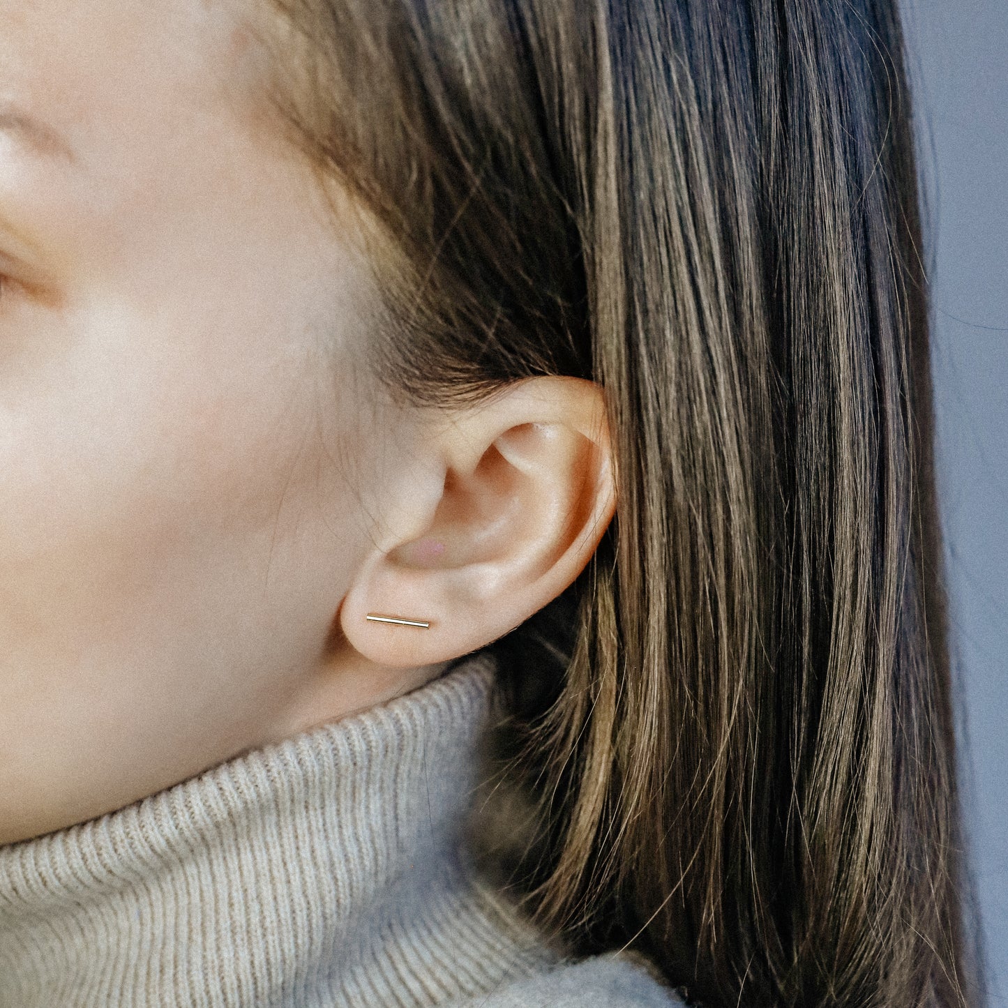 Minimal bar screw back earring in gold finish displayed on white background
