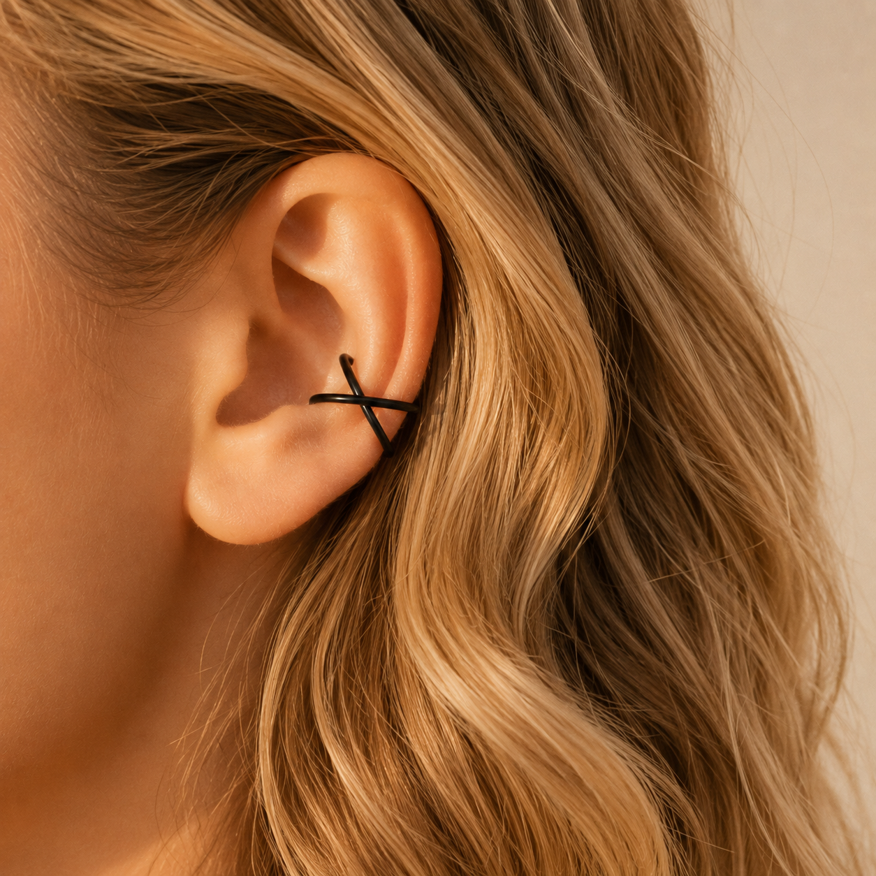 Black no piercing criss cross ear cuff shown on the upper ear, featuring a modern wraparound conch style.