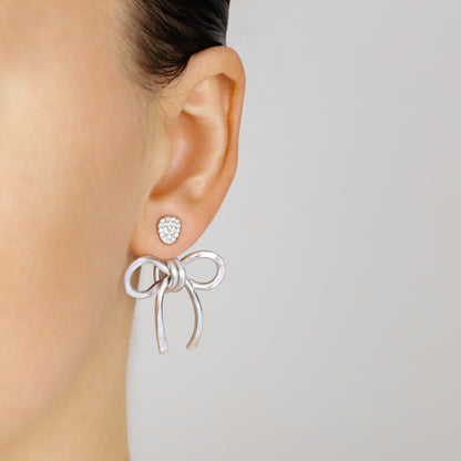 Silver medium bow ear jacket worn behind the earlobe with a sparkling stud, highlighting the lightweight hammered aluminum design.
