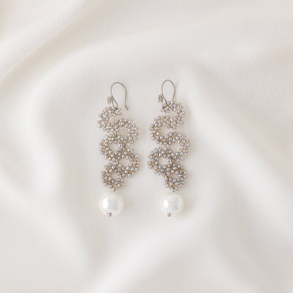 Champagne crystal cascading snake earrings with pearl drop on soft white fabric