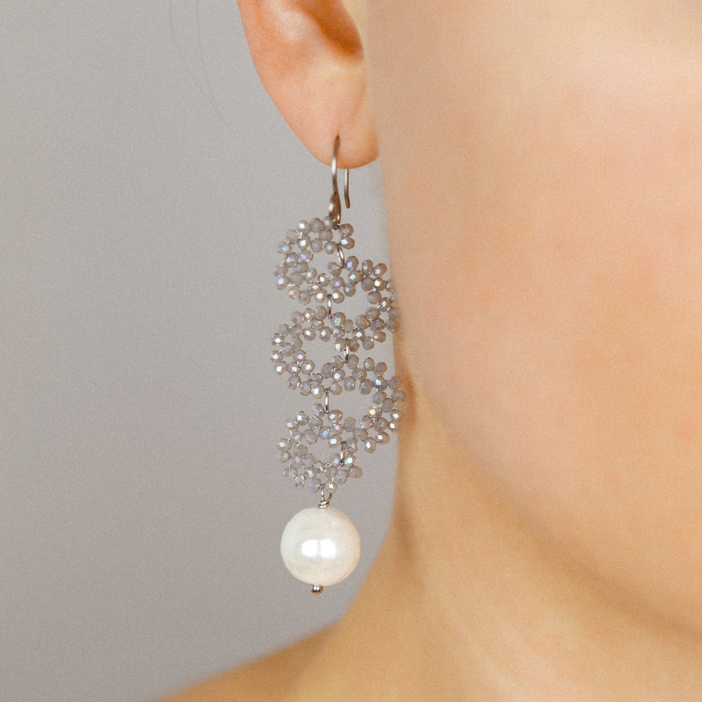 Champagne iridescent crystal snake drop earrings with ceramic pearl worn by a model