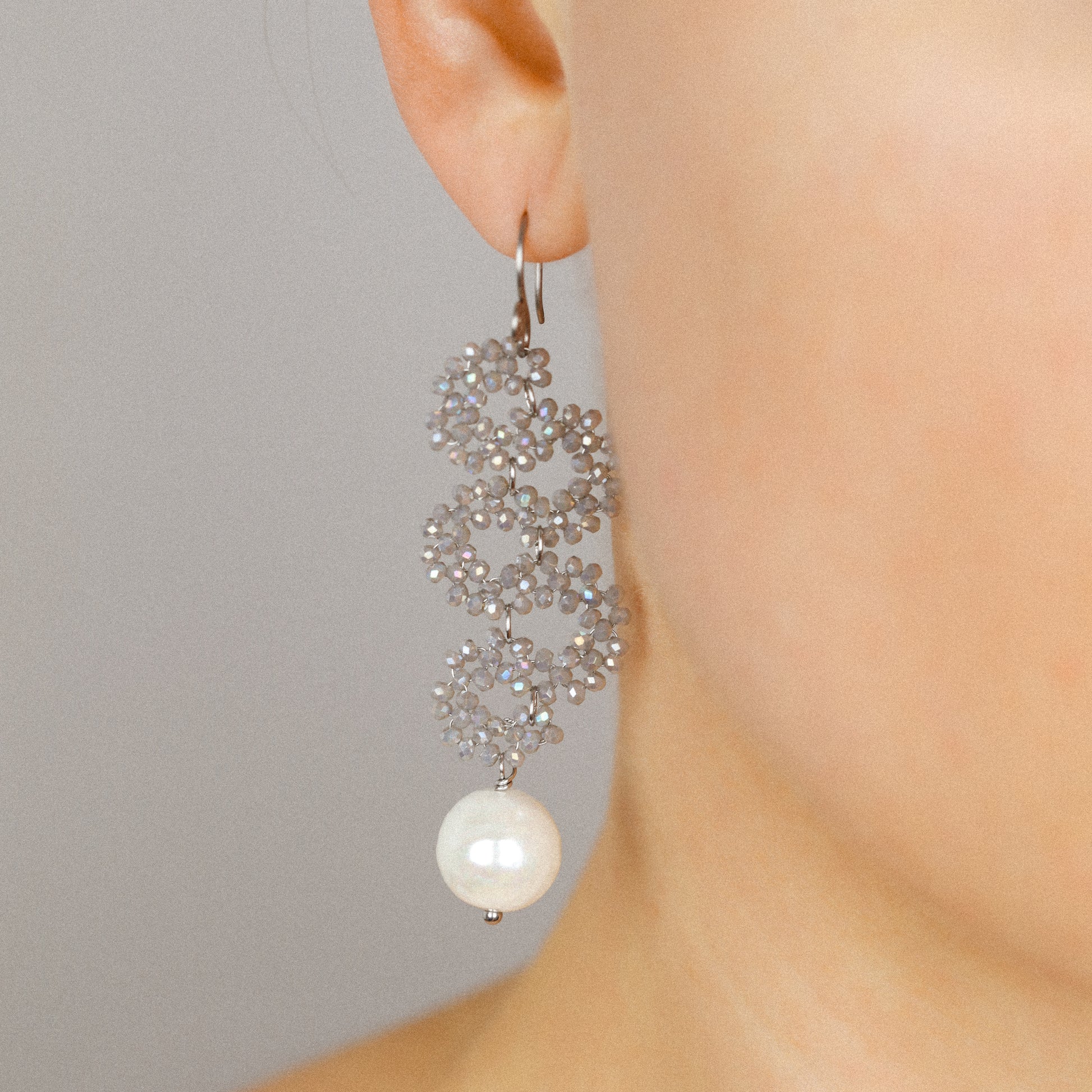 Champagne iridescent crystal snake drop earrings with ceramic pearl worn by a model