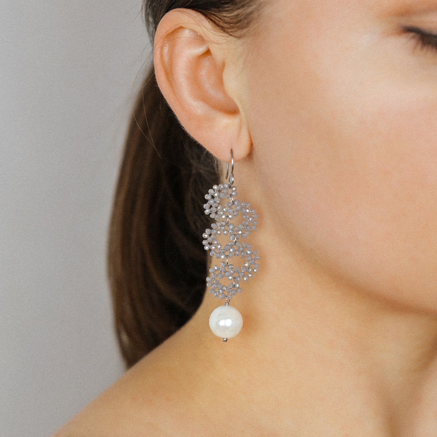Close-up of champagne iridescent crystal earrings with ceramic pearl drop