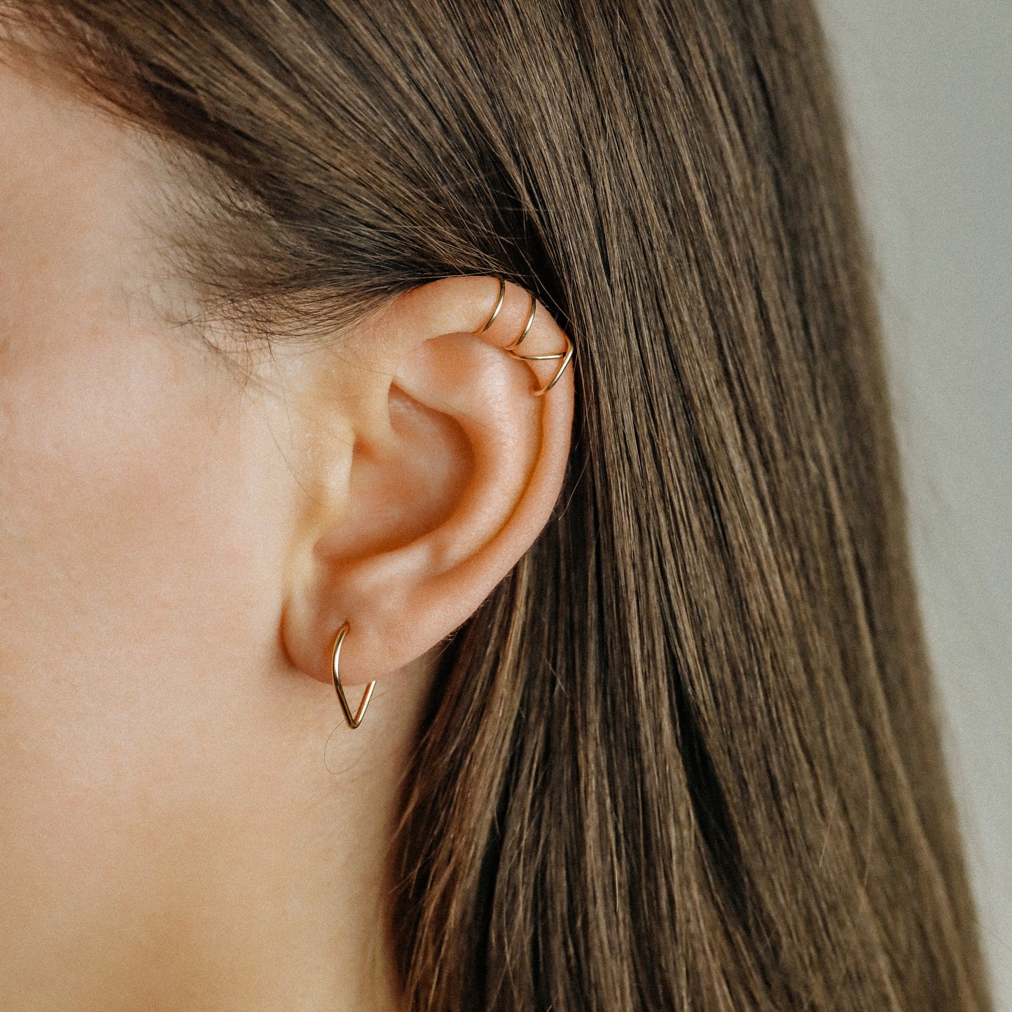 Model wearing a gold chevron septum ring with a minimal V-shaped front.