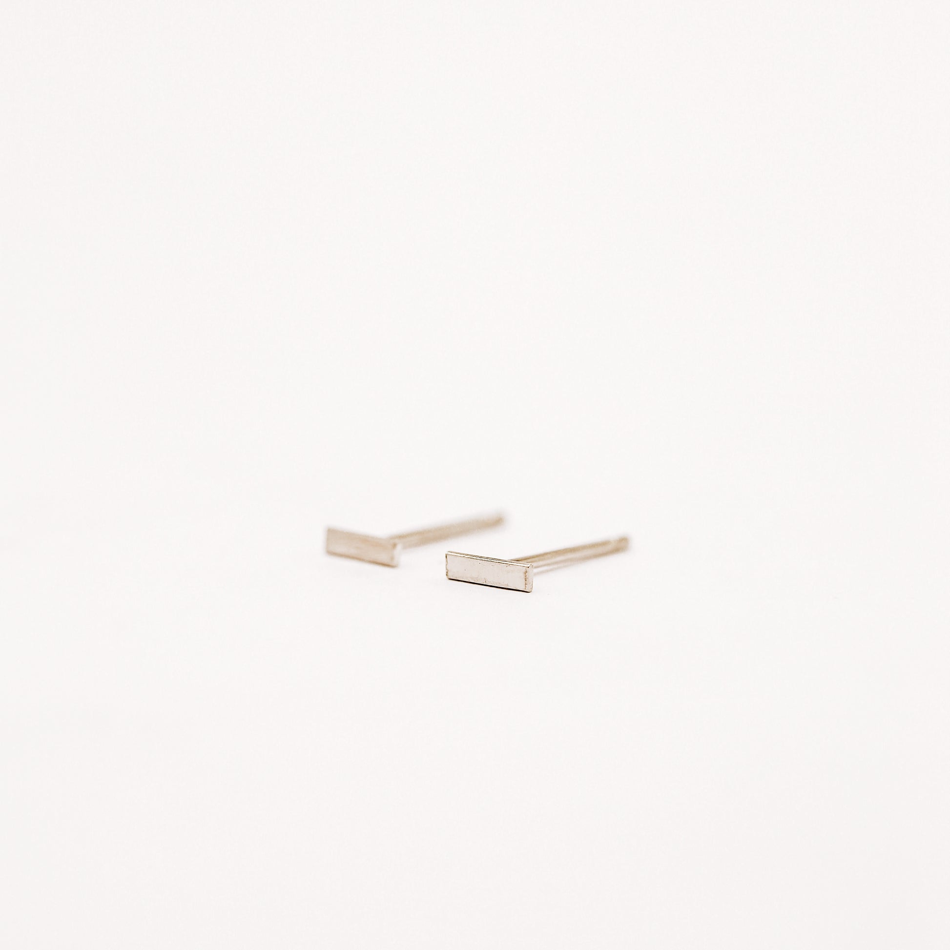 Tiny rectangle bar stud earrings in solid 925 sterling silver on white background