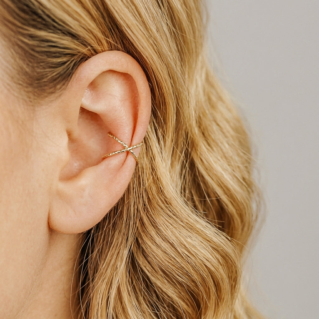 Diamond cut gold criss cross ear cuff worn on the upper ear, designed as a no piercing conch ear cuff with sparkling textured finish.