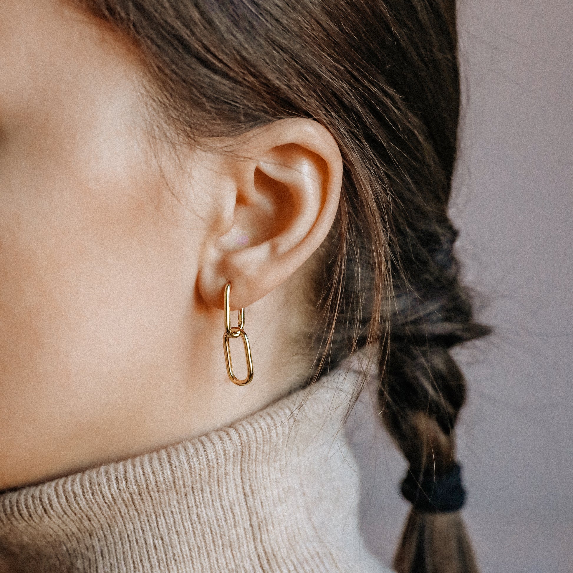 Close up of gold double open-link earrings with polished geometric silhouette