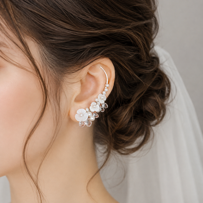 Bridal ear crawler worn with a formal updo and veil, decorated with genuine freshwater pearls, luminous flower shapes and clear crystal briolettes for a detailed wedding look.