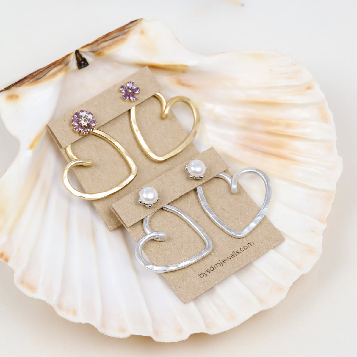 Handmade open heart Ear Jacket earrings designed to sit behind the pierced earlobe beneath an interchangeable stud, available as one Ear Jacket or a matching pair in gold or silver hammered aluminum, approximately 25 mm in diameter, with one coordinating pair of stainless steel post stud earrings included with each order; stud designs vary according to current availability and those shown in the photos are styling examples rather than guaranteed designs.