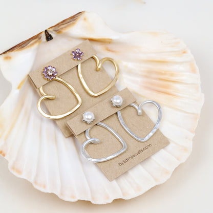 Handmade open heart Ear Jacket earrings designed to sit behind the pierced earlobe beneath an interchangeable stud, available as one Ear Jacket or a matching pair in gold or silver hammered aluminum, approximately 25 mm in diameter, with one coordinating pair of stainless steel post stud earrings included with each order; stud designs vary according to current availability and those shown in the photos are styling examples rather than guaranteed designs.