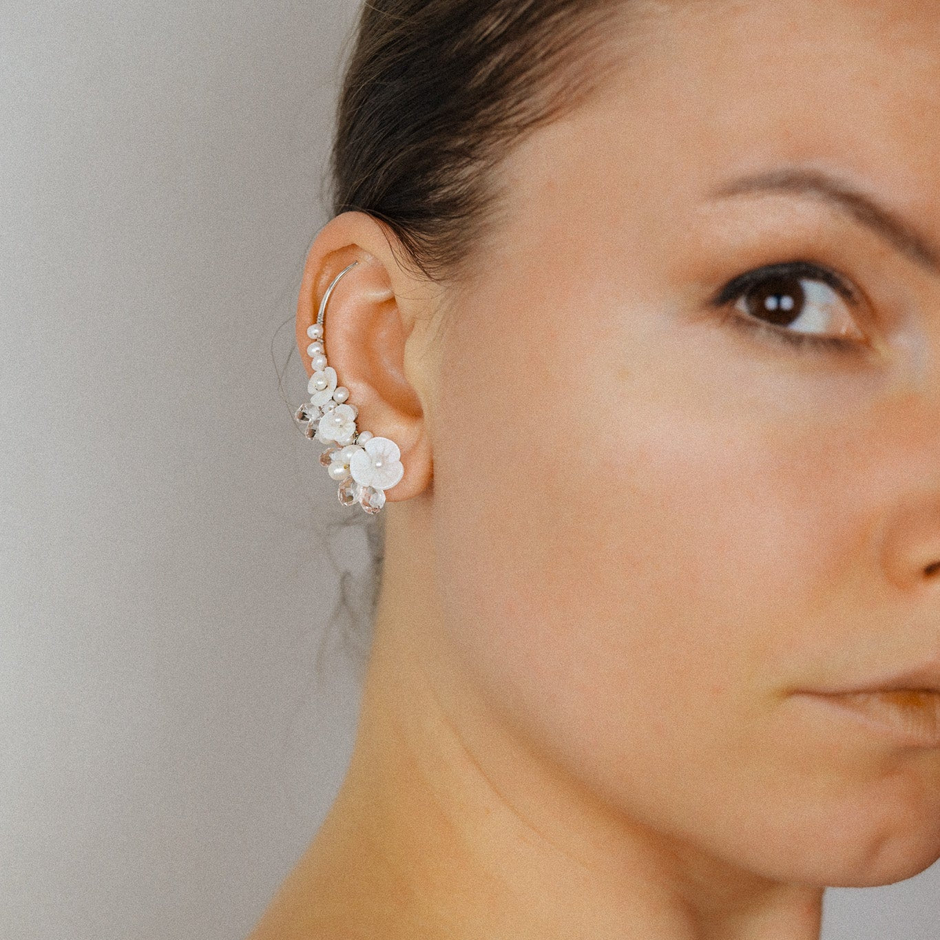 Bride wearing floral pearl ear climbers with mother of pearl flowers and crystal drops