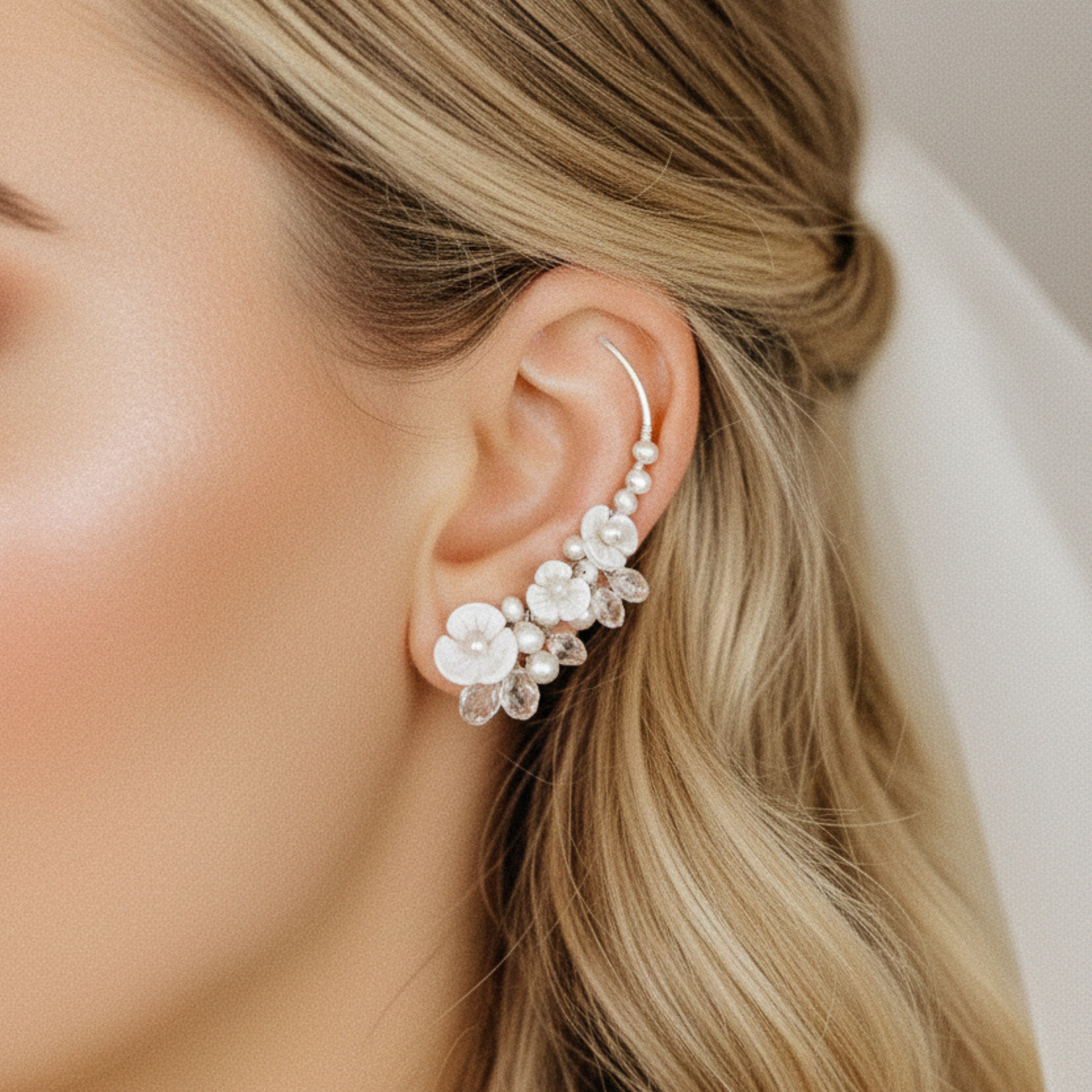 Bride wearing floral pearl ear climbers with mother of pearl flowers and crystal drops