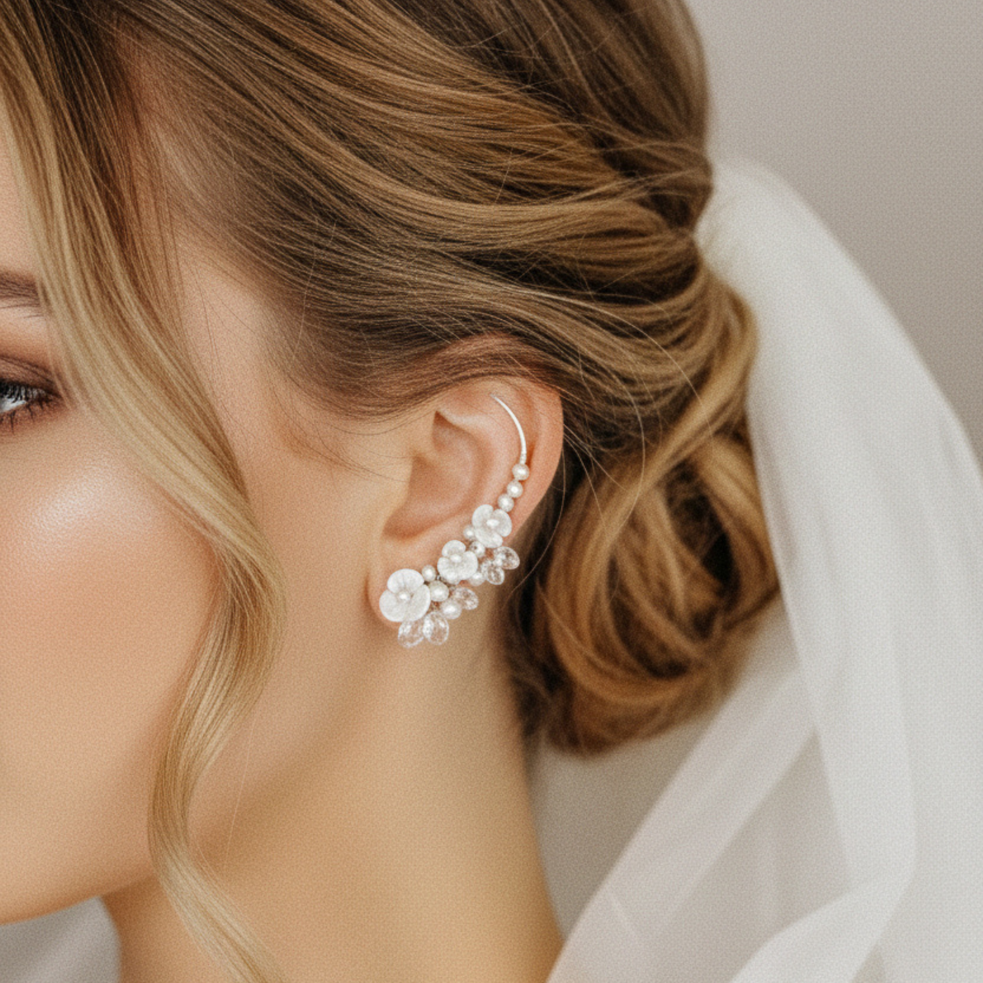 Bride wearing floral pearl ear climbers with mother of pearl flowers and crystal drops